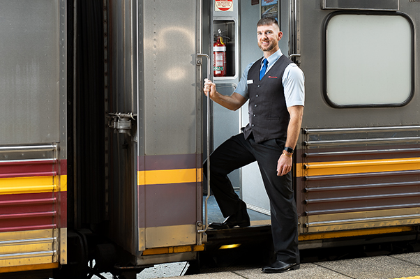 An Onboard team member steps off the train onto the platform.