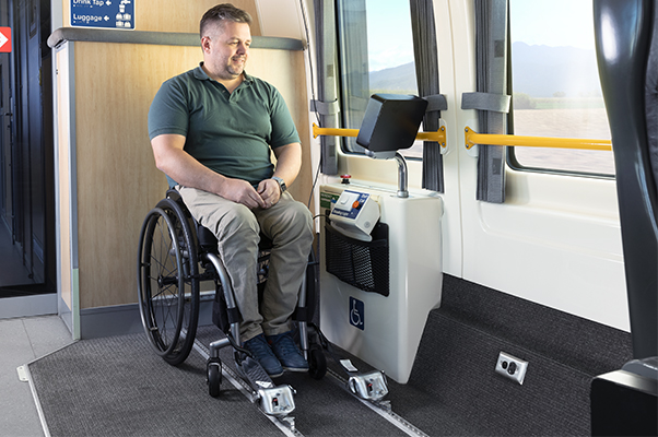 A Customer watches the onboard entertainment in a wheelchair secured with tie down straps.